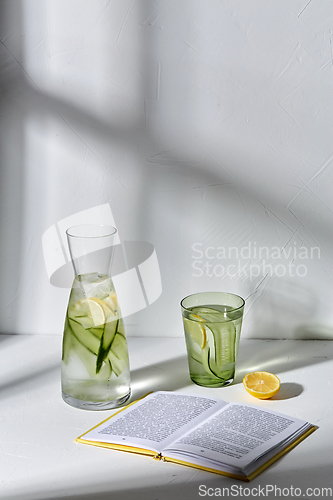 Image of glass of water with lemon and cucumber and book