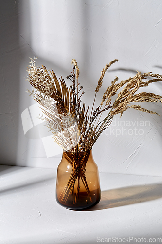 Image of decorative dried flowers in brown glass vase