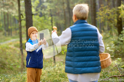 Image of grandson photographing grandmother with mushroom