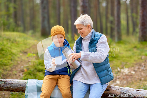 Image of grandmother with grandson drinking tea in forest