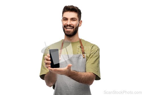 Image of happy smiling barman in apron showing smartphone