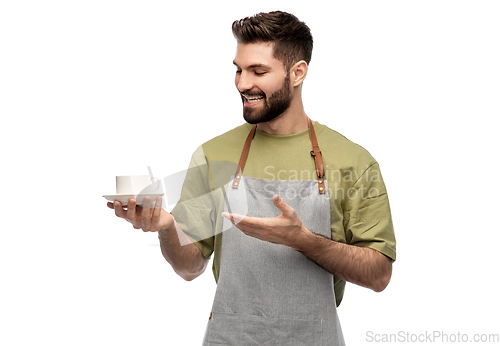 Image of happy smiling waiter in apron with cup of coffee