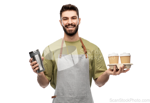 Image of happy waiter with takeout coffee cups and tumbler