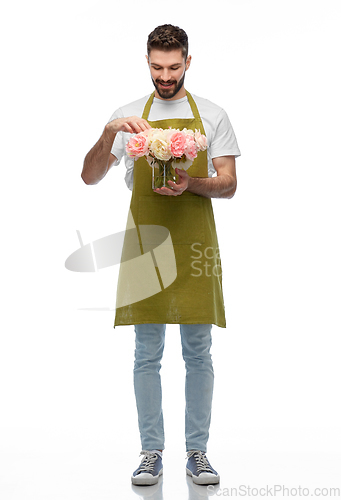 Image of happy smiling male gardener with flowers in vase