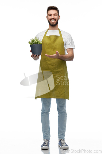 Image of happy smiling male gardener with flower in pot