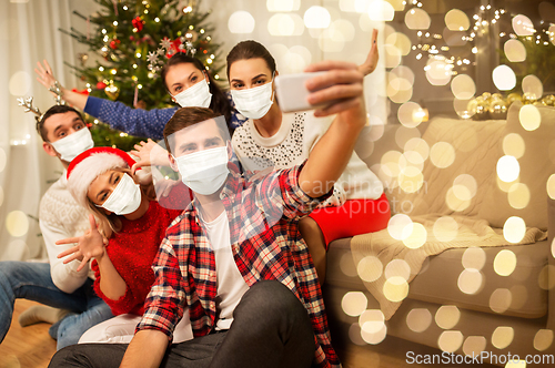 Image of friends in masks taking selfie at christmas party