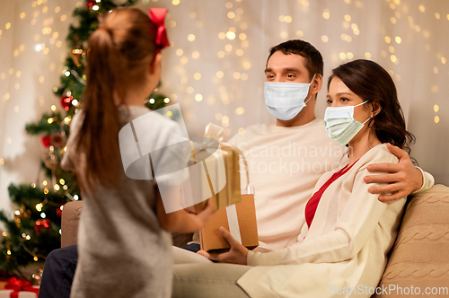 Image of family in masks with christmas presents at home