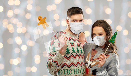 Image of couple in medical masks and christmas sweaters