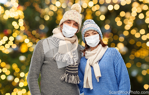 Image of couple in masks and winter clothes on christmas