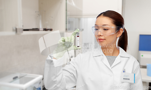 Image of asian female doctor holding beaker with blood test