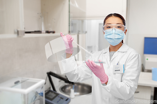 Image of asian female scientist in mask working on vaccine