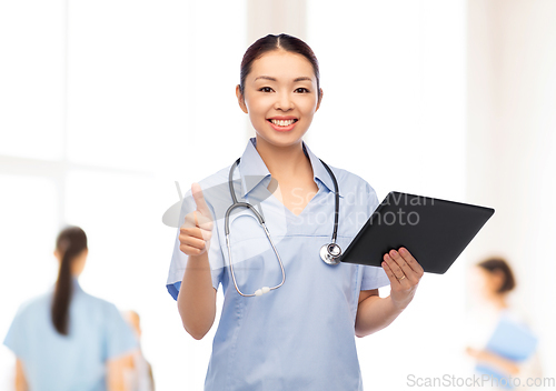 Image of nurse with tablet pc shows thumbs up at hospital