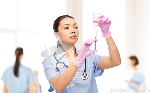 Image of asian female nurse with medicine and syringe