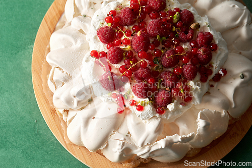 Image of pavlova meringue cake with berries on wooden board