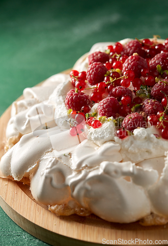 Image of pavlova meringue cake with berries on wooden board