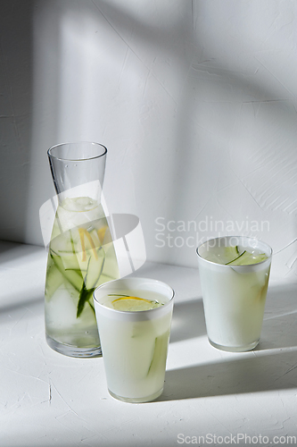 Image of glasses with lemon water and cucumber on table