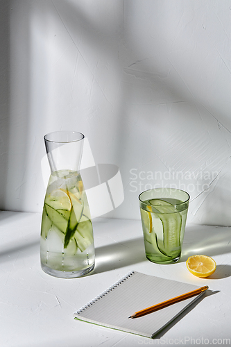 Image of water with lemon and cucumber and notebook