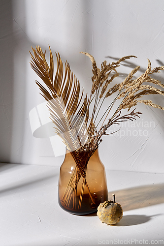 Image of decorative dried flowers in glass vase and pumpkin