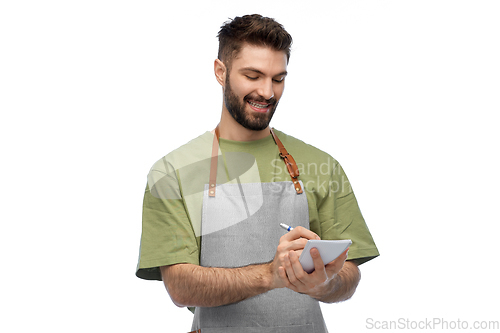 Image of smiling waiter in apron taking notes to notepad
