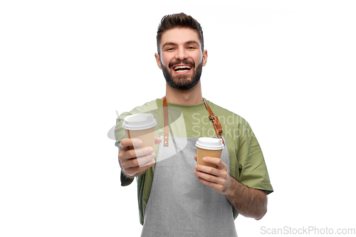 Image of happy smiling barman in apron with takeaway coffee