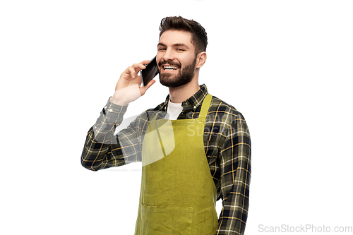 Image of happy male gardener in apron calling on smartphone