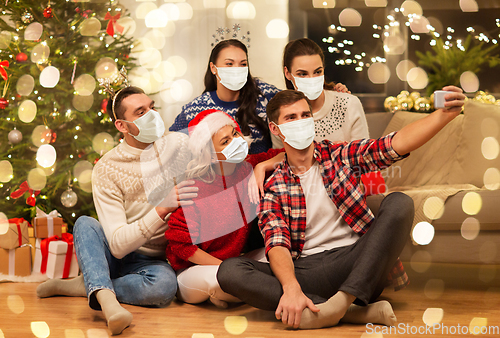 Image of friends in masks taking selfie at christmas party