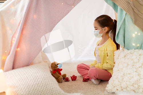 Image of little girl playing tea party in kids tent at home