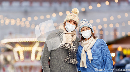 Image of couple in masks and winter clothes on christmas