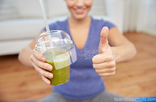 Image of happy woman with cup of smoothie showing thumbs up