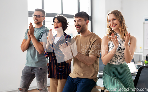 Image of happy business team applauding at office