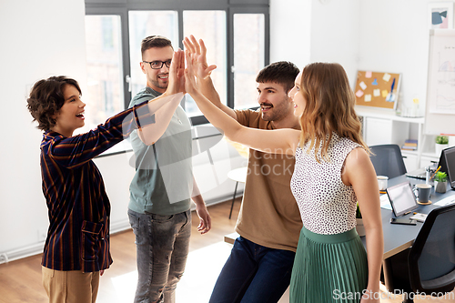 Image of happy business team making high five at office