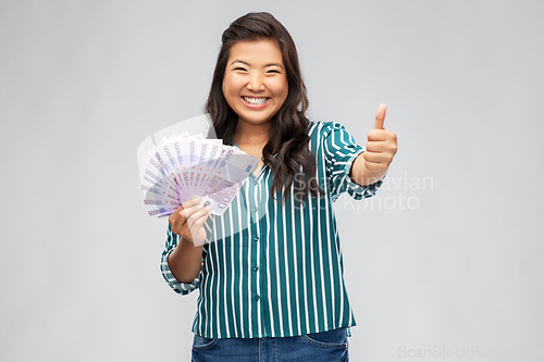 Image of asian woman with euro money showing thumbs up