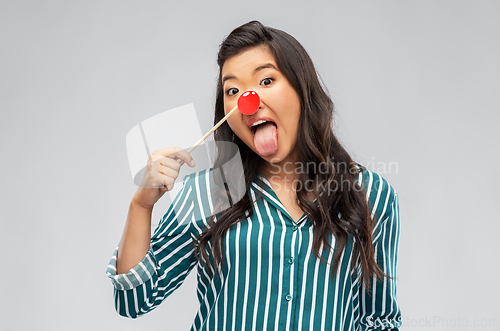 Image of asian woman with red clown nose showing tongue