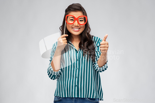 Image of asian woman with party glasses showing thumbs up