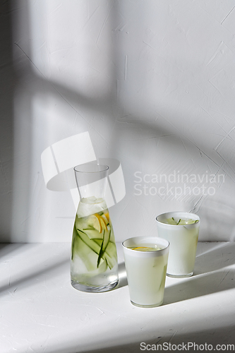 Image of glasses with lemon water and cucumber on table