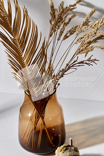 Image of decorative dried flowers in glass vase and pumpkin