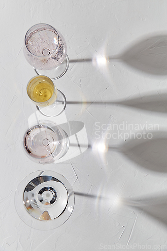 Image of wine glasses dropping shadows on white surface