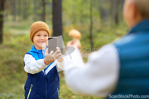 Image of grandson photographing grandmother with mushroom