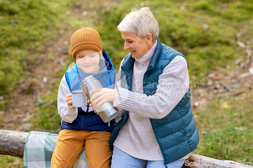 Image of grandmother with grandson drinking tea in forest