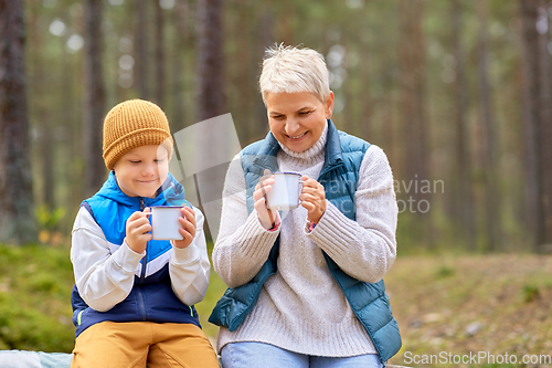 Image of grandmother with grandson drinking tea in forest