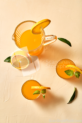 Image of glasses with orange juice and peppermint on table