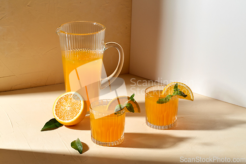 Image of glasses with orange juice and peppermint on table