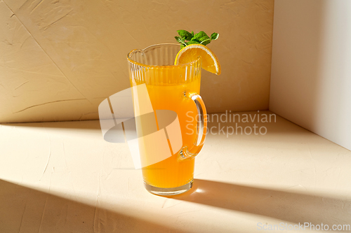 Image of jug with orange juice and peppermint on table