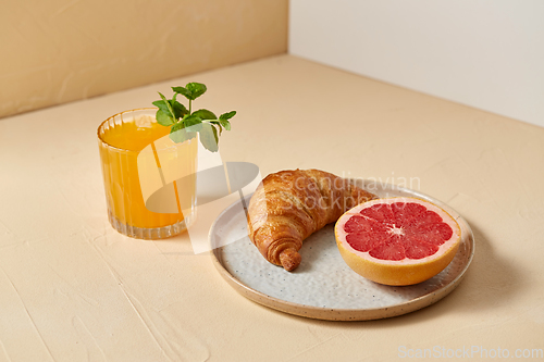 Image of orange juice, croissant and grapefruit on plate