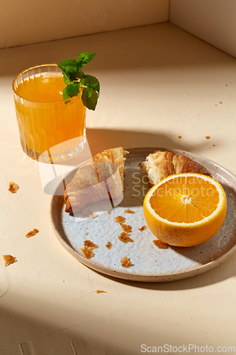 Image of glass of orange juice and croissant on plate