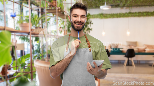 Image of smiling waiter with pen and notepad at restaurant