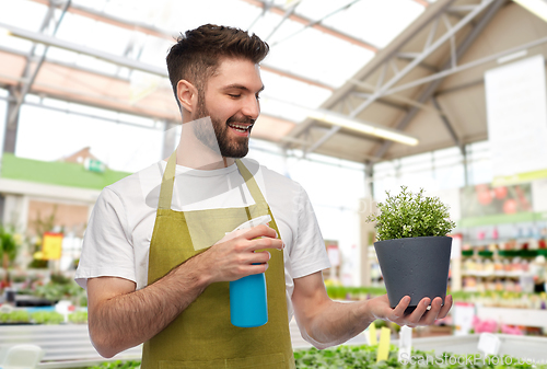 Image of happy male gardener moisturizing flower at shop