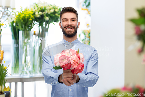 Image of happy smiling man with peonies at flower shop