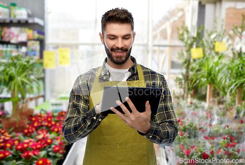 Image of gardener or seller with tablet pc at flower shop