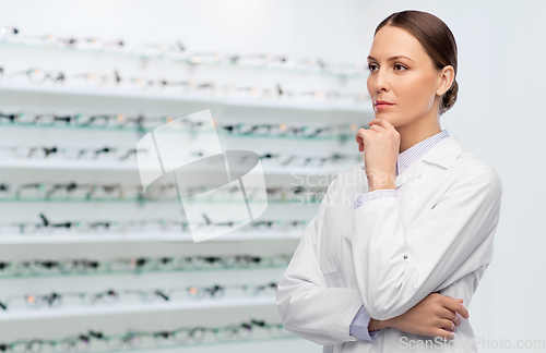 Image of thinking female doctor in coat at optical store
